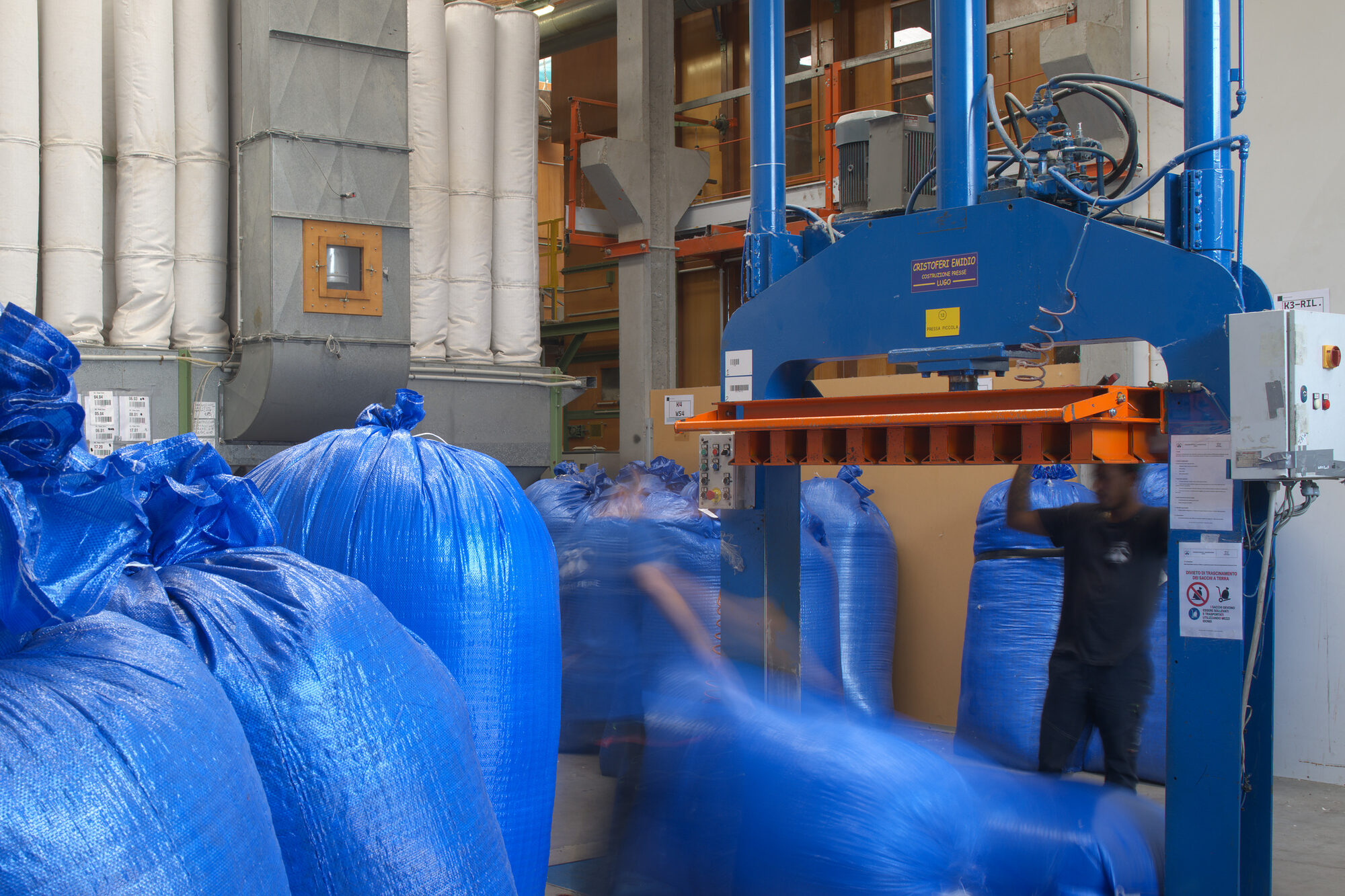 Un operatore alla pressa idraulica fra i big bag di piuma pronti per l’imballo